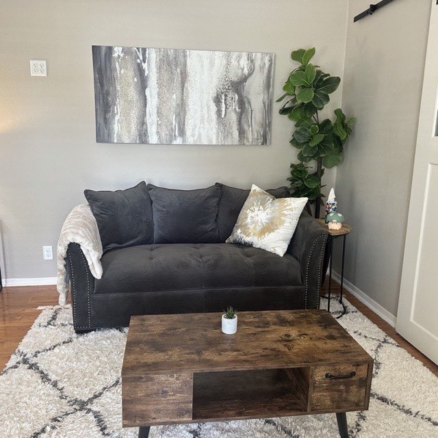 A counseling room at the Katy office with a soft grey sofa, a throw blanket, and a fiddle-leaf fig